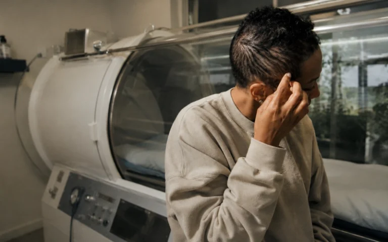 Adult showing new temple hair beside a hyperbaric chamber.