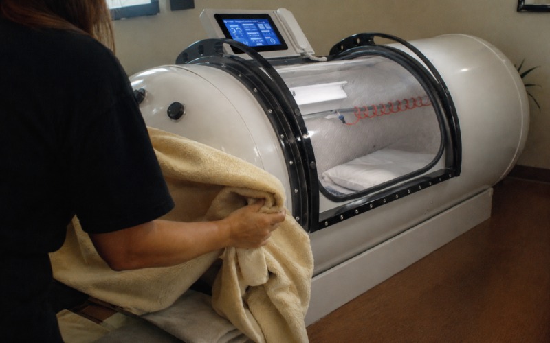 A person quietly preparing beside a hyperbaric chamber
