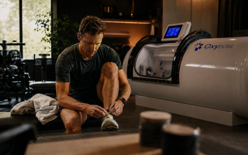 Athlete preparing for recovery beside a hyperbaric chamber